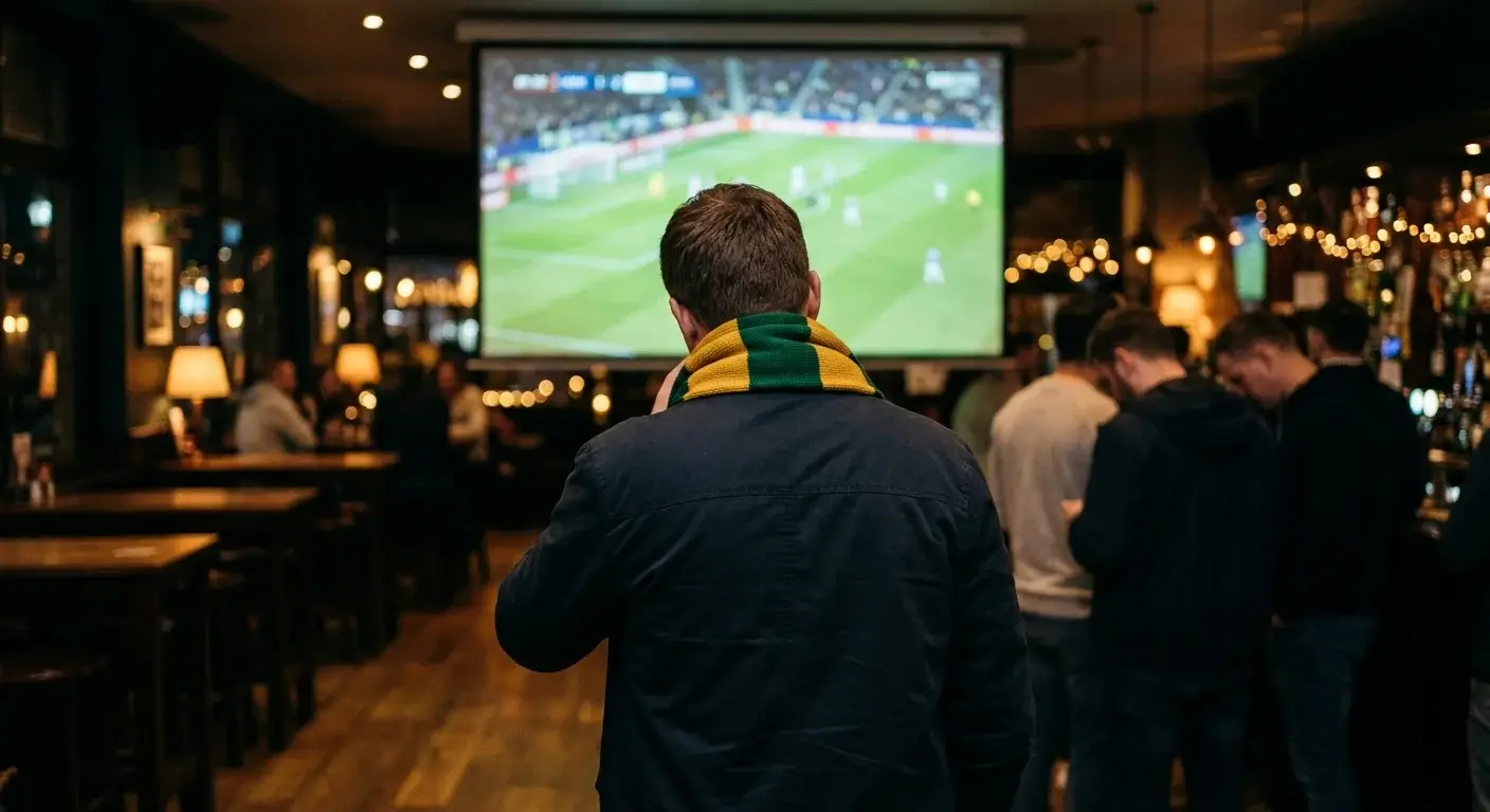 A lone Socceroos fan in green and gold scarf watching the closing moments of a World Cup match on a big screen
